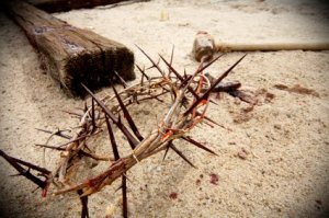 easter scene with crown of thorns, hammer and nails with blood on sand